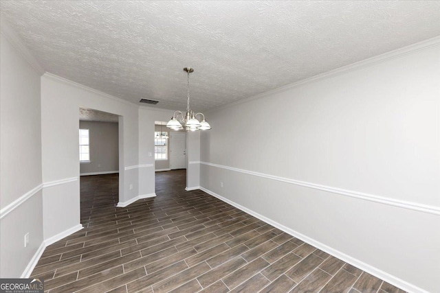 unfurnished dining area with a textured ceiling, ornamental molding, and an inviting chandelier