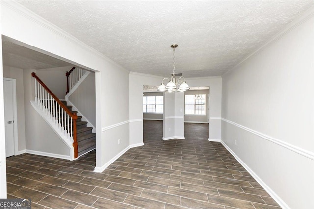 unfurnished dining area with a textured ceiling, ornamental molding, and a notable chandelier