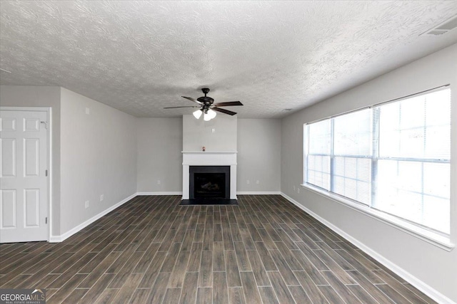 unfurnished living room featuring dark wood-type flooring, a textured ceiling, and ceiling fan