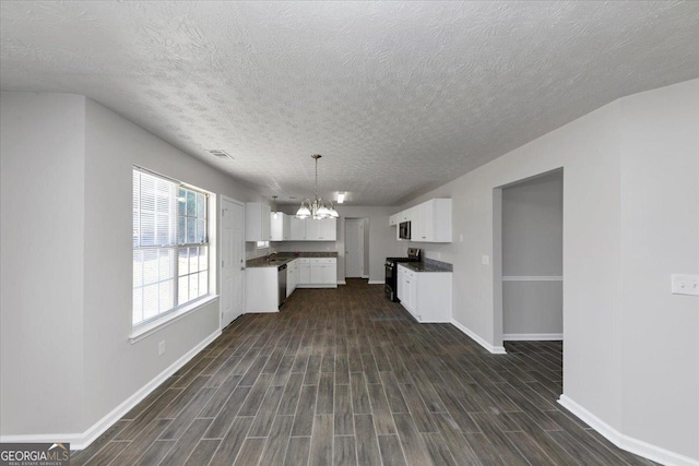 kitchen featuring pendant lighting, white cabinets, appliances with stainless steel finishes, dark wood-type flooring, and an inviting chandelier