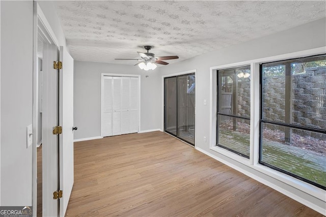 empty room with a healthy amount of sunlight, a textured ceiling, and light wood-type flooring