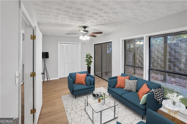 living room with light wood-type flooring, a textured ceiling, and ceiling fan