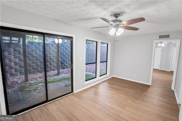 unfurnished room featuring hardwood / wood-style flooring, plenty of natural light, a textured ceiling, and ceiling fan