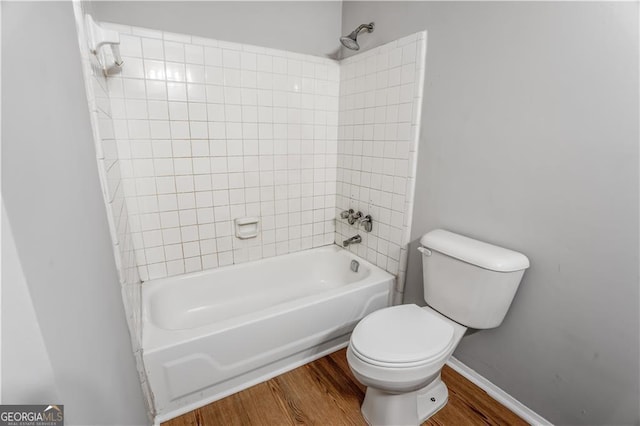 bathroom with toilet, tiled shower / bath, and hardwood / wood-style floors