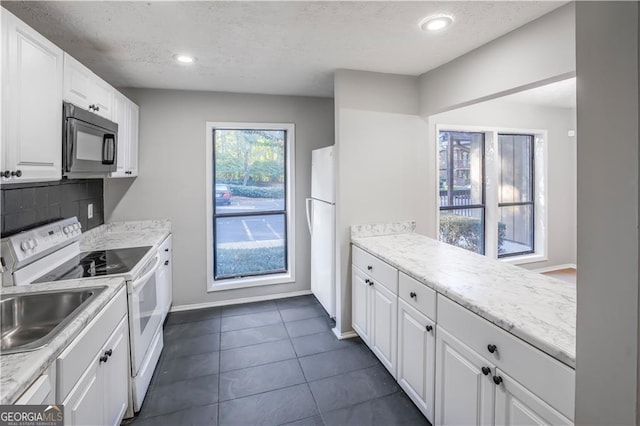 kitchen featuring dark tile patterned flooring, white appliances, white cabinets, a textured ceiling, and backsplash