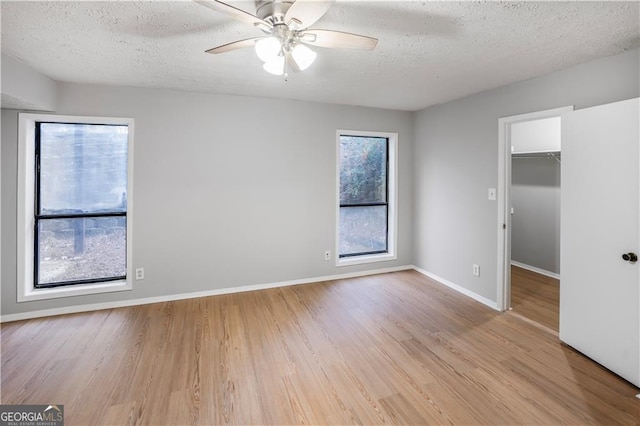 spare room with ceiling fan, a textured ceiling, and light wood-type flooring