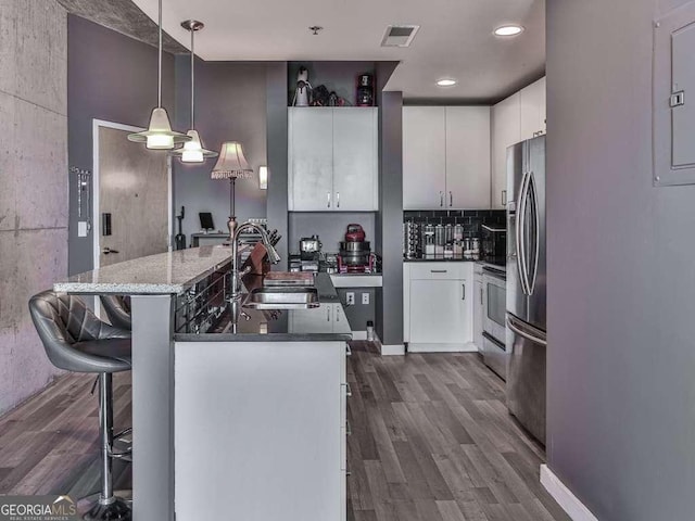 kitchen featuring decorative light fixtures, sink, white cabinets, and a breakfast bar