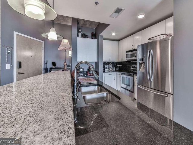 kitchen featuring decorative light fixtures, sink, white cabinetry, dark stone counters, and stainless steel appliances