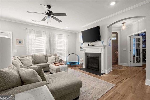 living room featuring ceiling fan, ornamental molding, and light hardwood / wood-style floors