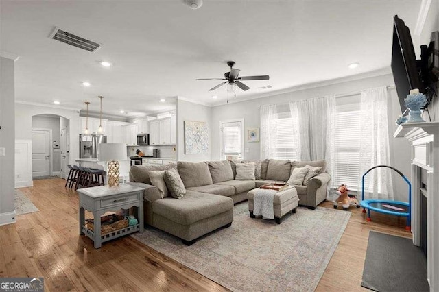 living room featuring ceiling fan, light hardwood / wood-style flooring, and crown molding