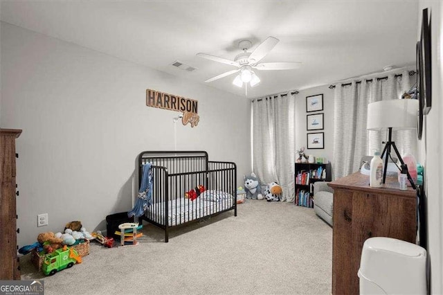 bedroom with ceiling fan, carpet, and a crib