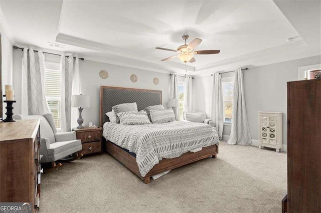 carpeted bedroom with ceiling fan, a raised ceiling, and ornamental molding