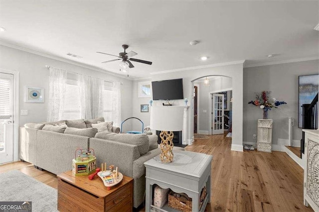 living room with a wealth of natural light, light hardwood / wood-style flooring, and crown molding