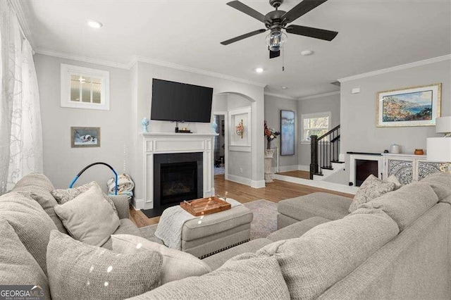 living room with light hardwood / wood-style floors, crown molding, and ceiling fan