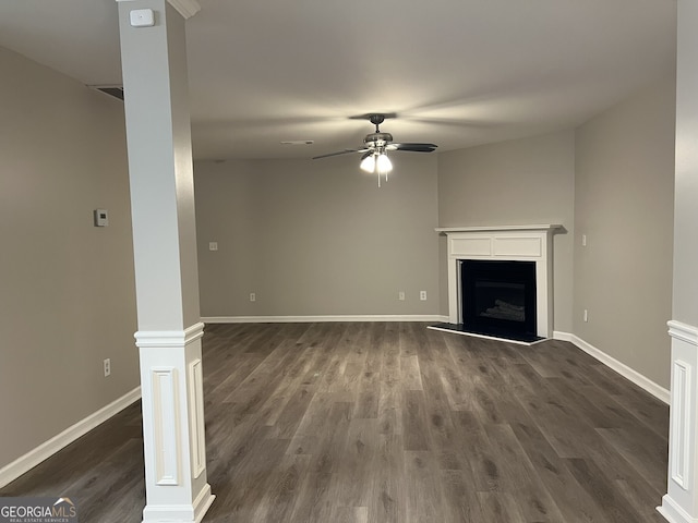 unfurnished living room featuring ceiling fan, dark hardwood / wood-style flooring, and ornate columns