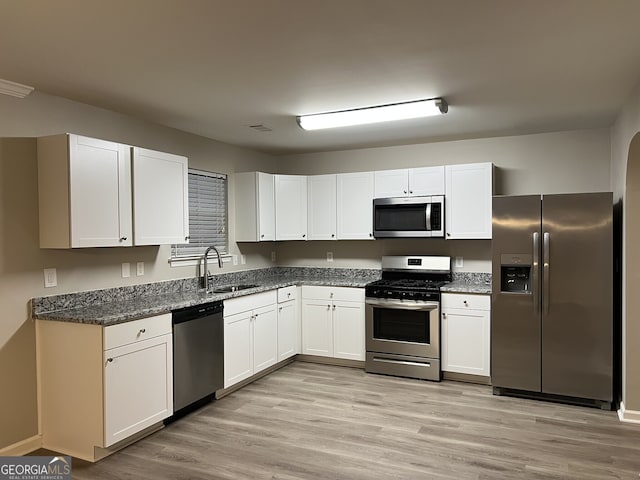 kitchen with sink, white cabinets, light hardwood / wood-style flooring, and appliances with stainless steel finishes