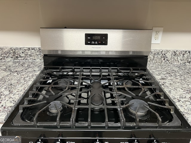 room details with light stone counters and range with gas stovetop