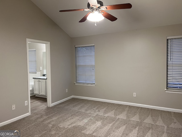 unfurnished bedroom with ceiling fan, ensuite bathroom, vaulted ceiling, and carpet floors