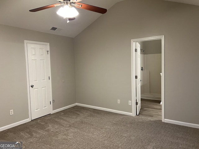 unfurnished bedroom with ceiling fan, dark carpet, ensuite bathroom, and lofted ceiling