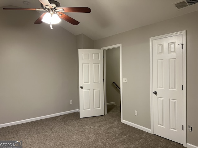 unfurnished bedroom with ceiling fan, dark colored carpet, and lofted ceiling