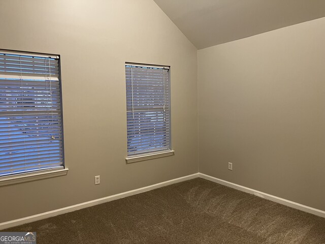 carpeted empty room featuring vaulted ceiling