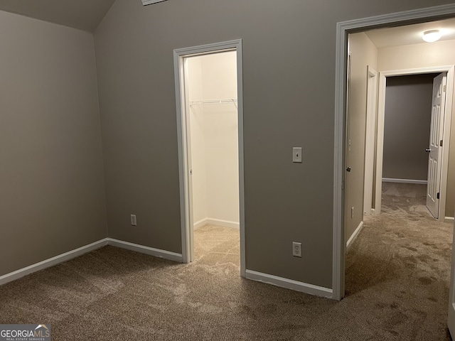 unfurnished bedroom featuring a closet, a spacious closet, and carpet floors