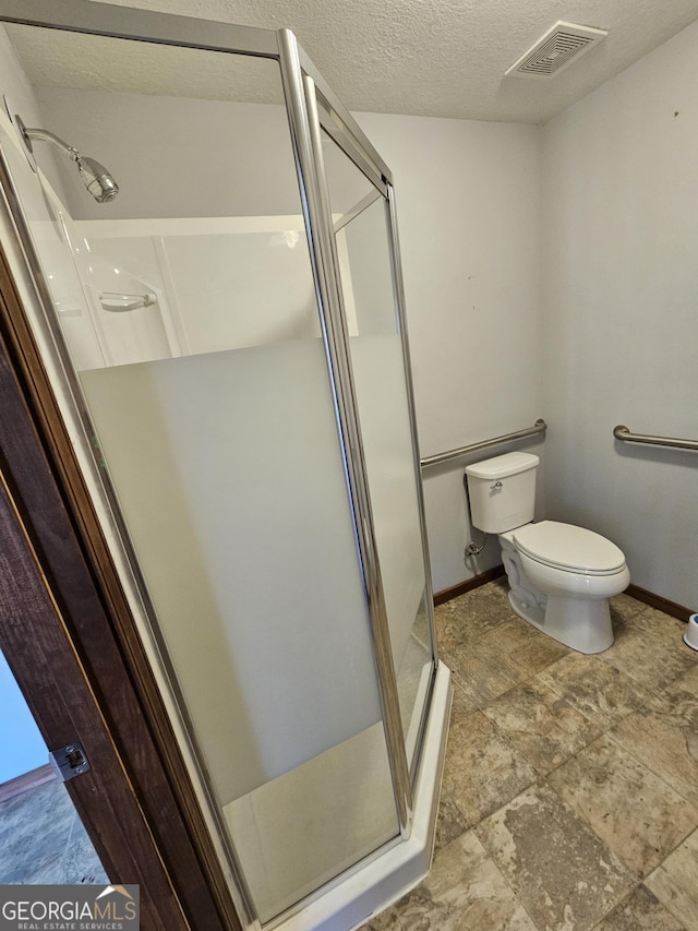 bathroom with toilet, a textured ceiling, and walk in shower