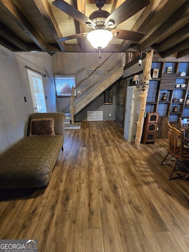 basement featuring wood-type flooring, ceiling fan, and wood walls