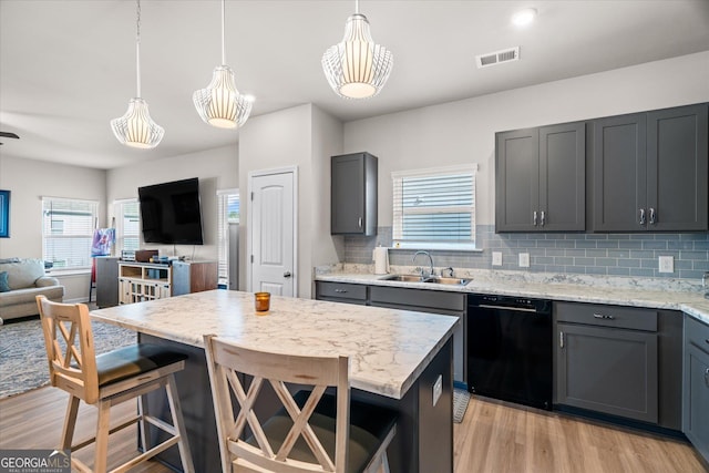 kitchen with sink, decorative light fixtures, a kitchen breakfast bar, dishwasher, and a kitchen island