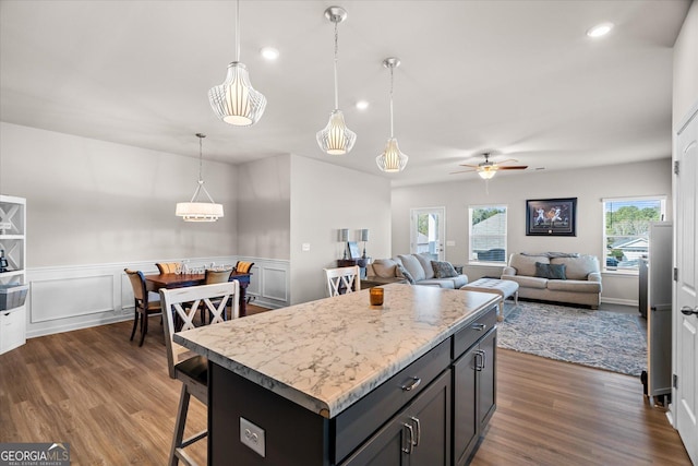 kitchen with decorative light fixtures, dark hardwood / wood-style floors, a breakfast bar area, and a center island