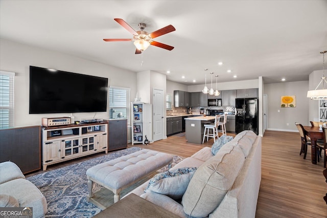 living room with ceiling fan, sink, and light wood-type flooring