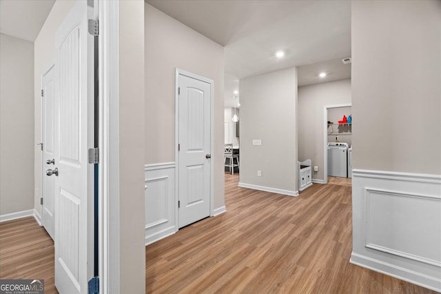 corridor featuring washer / clothes dryer and light wood-type flooring