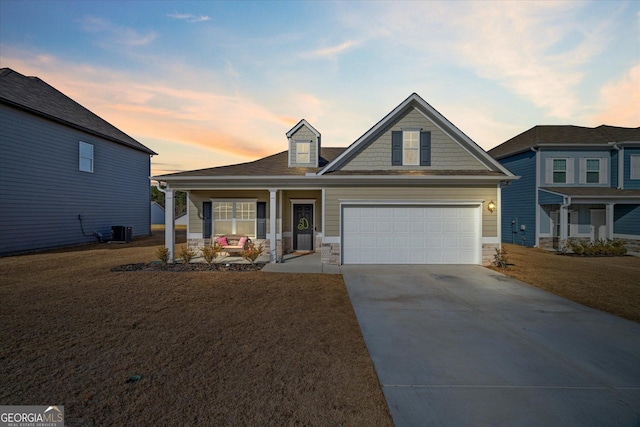 view of front facade with a yard, a garage, central AC, and covered porch