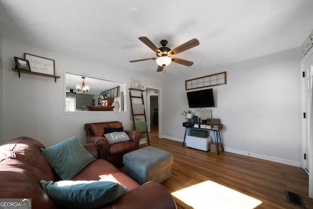 living room featuring ceiling fan with notable chandelier, a textured ceiling, and dark hardwood / wood-style flooring