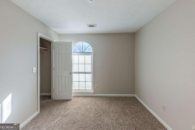 unfurnished bedroom featuring a closet, a textured ceiling, and light carpet