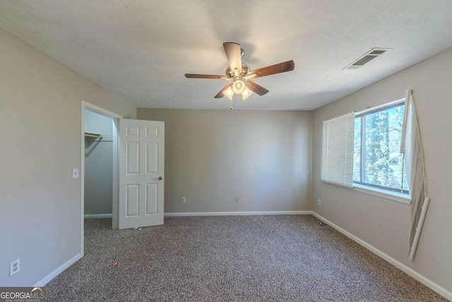 unfurnished bedroom with carpet, a spacious closet, and ceiling fan