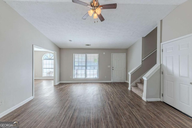 unfurnished living room featuring ceiling fan, dark hardwood / wood-style flooring, a textured ceiling, and lofted ceiling