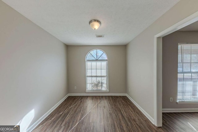 unfurnished room with dark hardwood / wood-style flooring and a textured ceiling