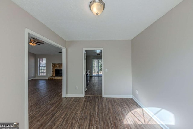 spare room with dark hardwood / wood-style floors and a stone fireplace