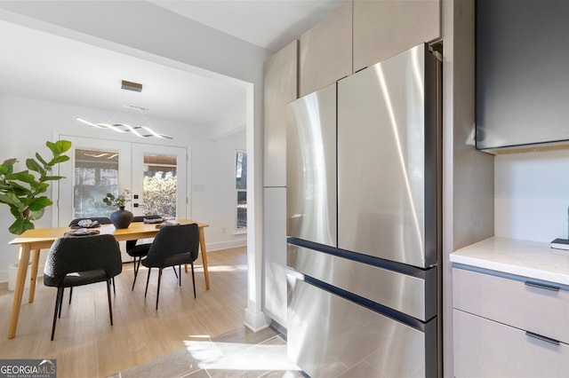 kitchen with french doors, light wood-type flooring, light stone countertops, and stainless steel refrigerator