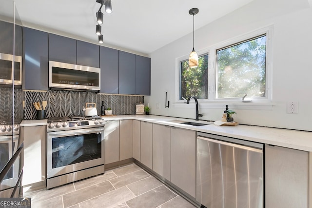 kitchen with appliances with stainless steel finishes, decorative light fixtures, sink, backsplash, and gray cabinets