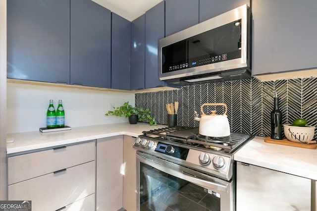 kitchen with light stone countertops, blue cabinetry, appliances with stainless steel finishes, and tasteful backsplash