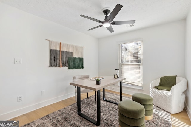 office space with ceiling fan, plenty of natural light, wood-type flooring, and a textured ceiling