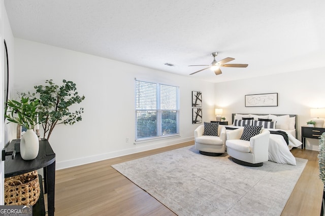 bedroom featuring ceiling fan, light hardwood / wood-style flooring, and a textured ceiling