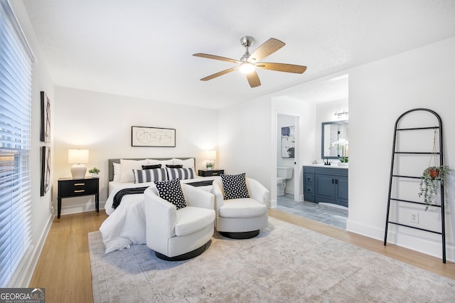 bedroom featuring ceiling fan, sink, connected bathroom, and light wood-type flooring