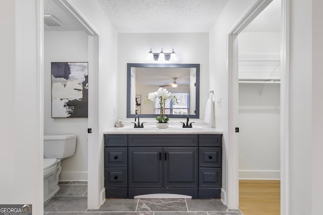 bathroom with toilet, a textured ceiling, and vanity