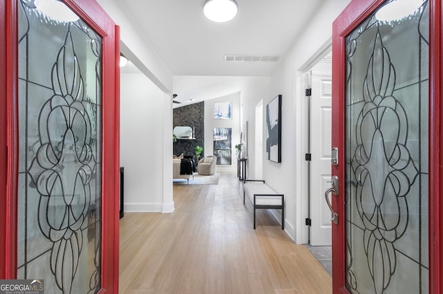 entrance foyer featuring a large fireplace, light hardwood / wood-style flooring, and lofted ceiling