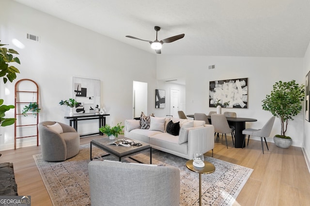 living room with ceiling fan, vaulted ceiling, and light wood-type flooring