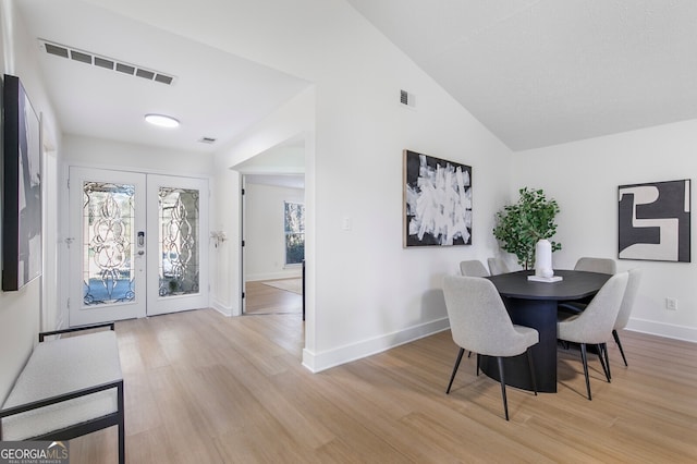 dining room with light wood-type flooring, french doors, and lofted ceiling