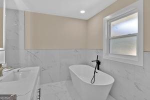 bathroom with tile walls, vanity, and a bathtub